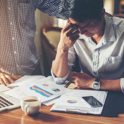 Serious young businessman looking at financial report seem like something mistake with his boss in office.